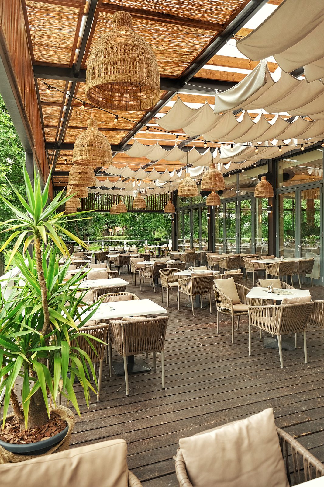 A Le Bistro fedett terasza fűzfonott lámpákkal és hangulatos ülőhelyekkel